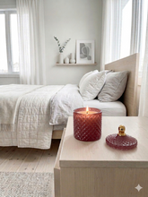 Load image into Gallery viewer, Essence pink glass geo soy candle. Cozy bedroom with a bed, nightstand, and decorative candles.