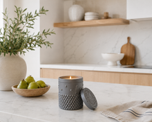 Load image into Gallery viewer, Essence black textured  luxury soy candle on a marble surface with pears and a plant in the background
